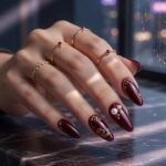 Unhas borgonha com efeito red carpet premium e detalhes dourados.